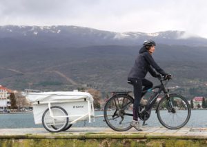 Ein Mann fährt auf einem Fahrrad und einem Hänger am Wasser vorbei
