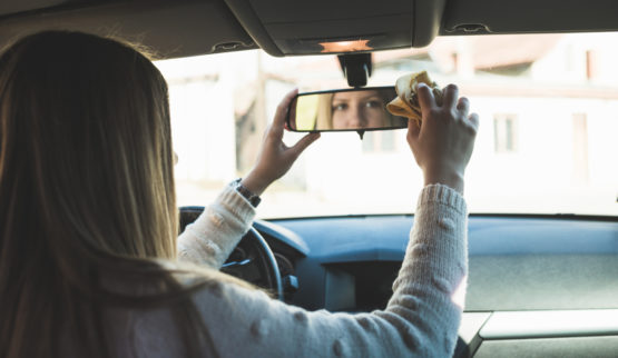 Eine Frau wischt über den Innenspiegel im Auto