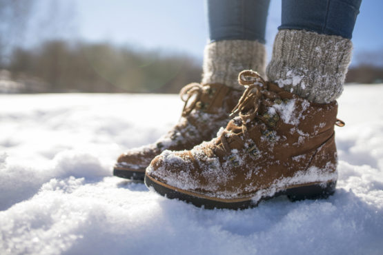Person trägt Winterschuhe und steht im Schnee