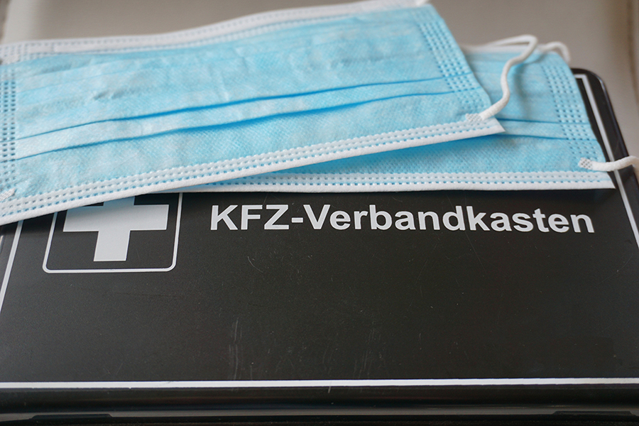 Auf einem Verbandskasten liegt ein Mundschutz