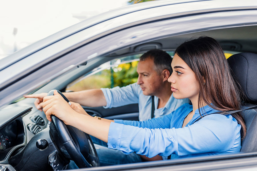 Fahrlehrer und Fahrschülerin sitzen im Auto