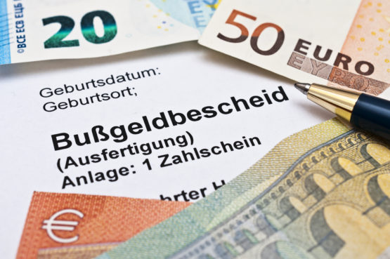 Auf einem Bußgeldbescheid liegen Euro scheine 