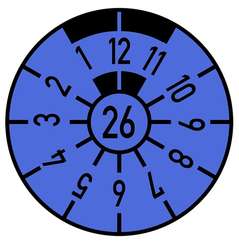 Blaue HU-Prüfplakette auf dem Kfz-Kennzeichen mit der Jahreszahl 26 in der Mitte und der Monatsmarkierung 12 oben, die den nächsten Prüftermin im Dezember 2026 anzeigt.