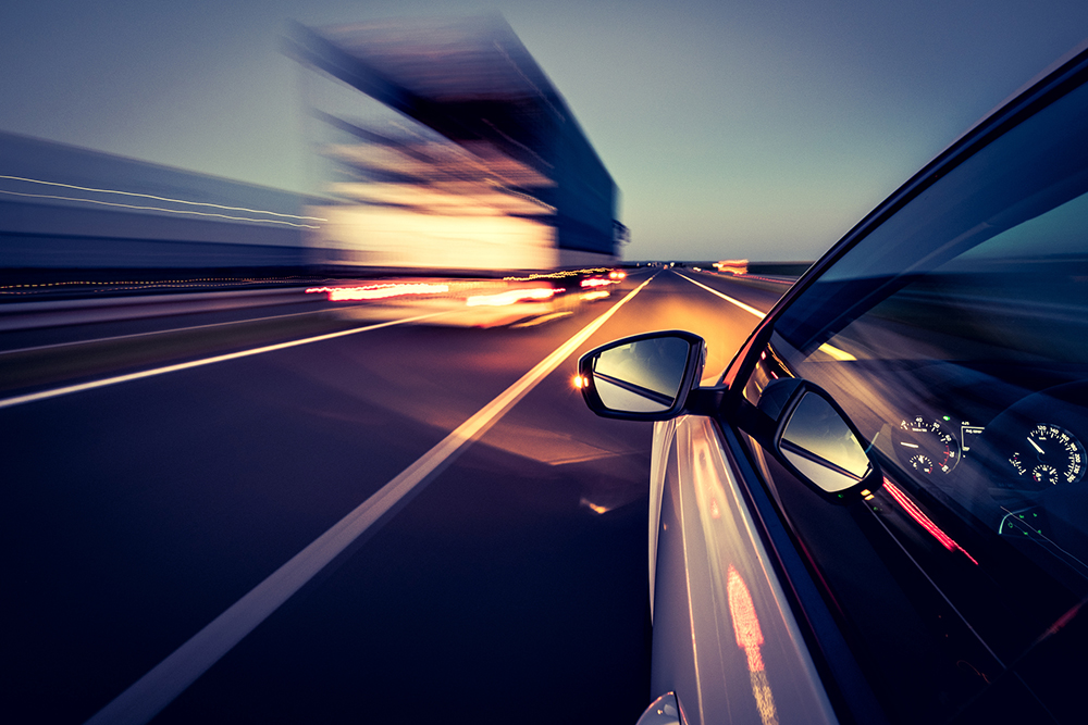 Ein Auto wird im Dunkeln von einem LKW rechts überholt