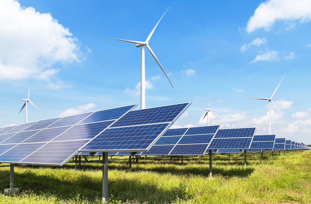 photovoltaikanlage auf einer wiese mit einem windrad im hintergrund