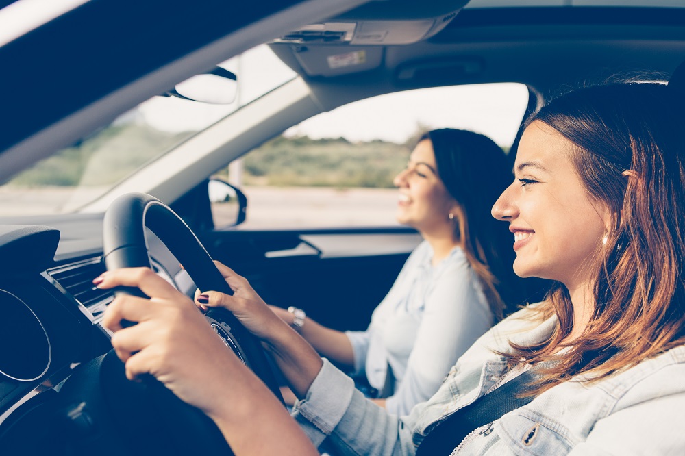 2 junge frauen sitzen lächelnd nebeneinander im auto