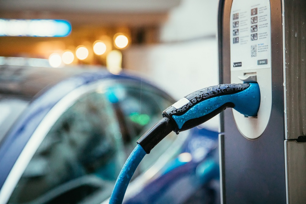 e-ladesäule mit unscharfem auto im hintergrund