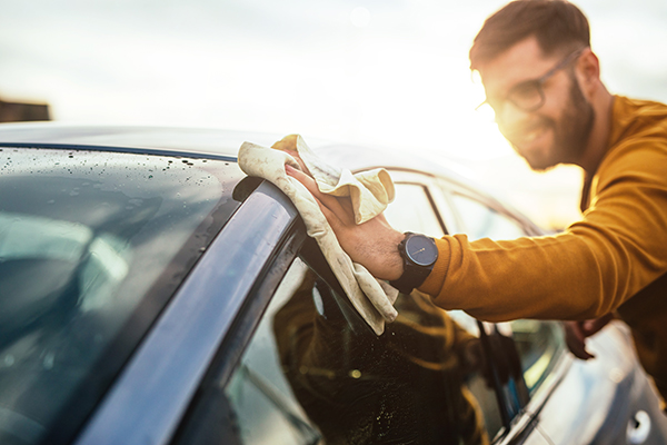 Ein Mann wischt mit einem Lappen über sein Auto